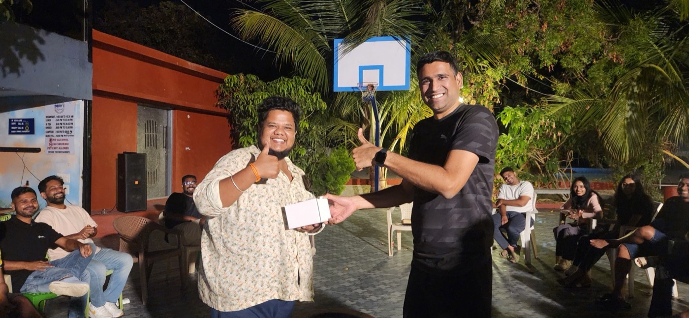 A teammate handing an award to a colleague during an evening recognition ceremony.