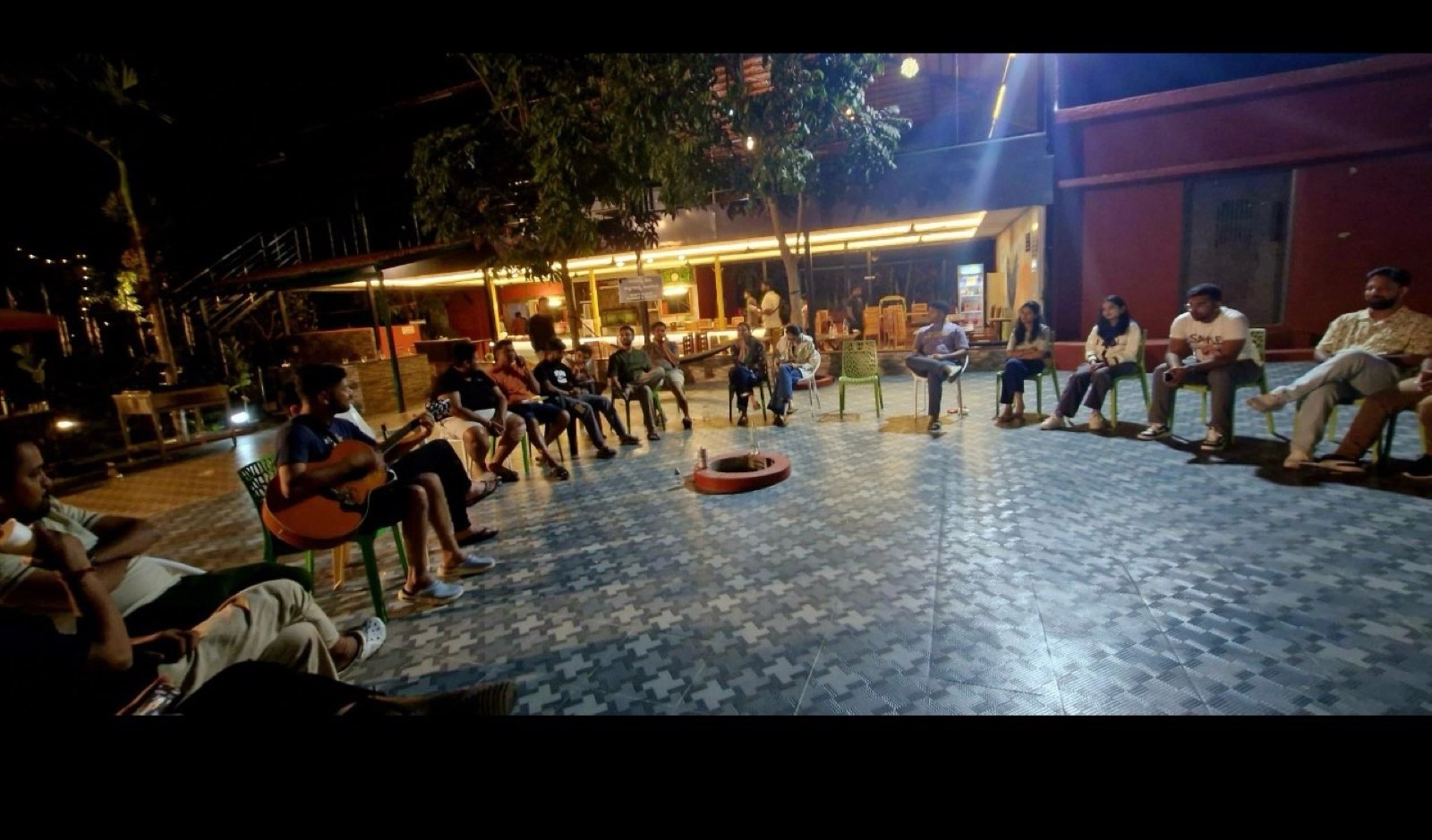 Night campfire circle at the offsite, one person playing guitar