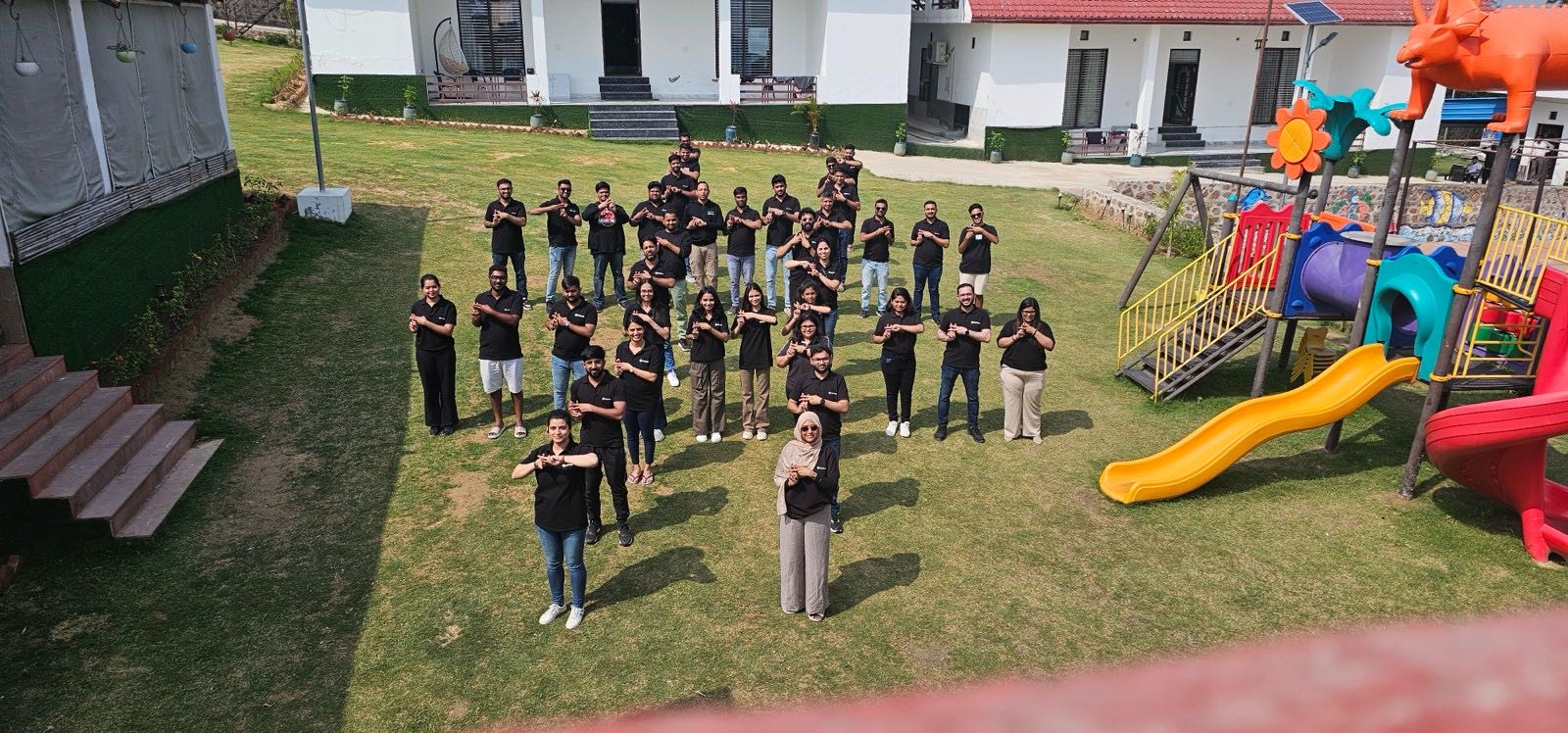 The whole Datahash team on the lawn at the Bengaluru offsite, making the Datahash X hand sign, photographed from above